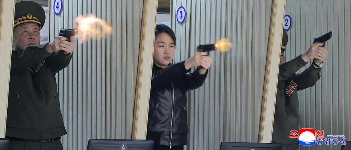 In this photo provided by the North Korean government, its leader Kim Jong Un's daughter, center, tries out a new pistol at a factory producing pistols and other light arms at an undisclosed place in North Korea Wednesday, March 11, 2026. (Korean Central News Agency/Korea News Service via AP)