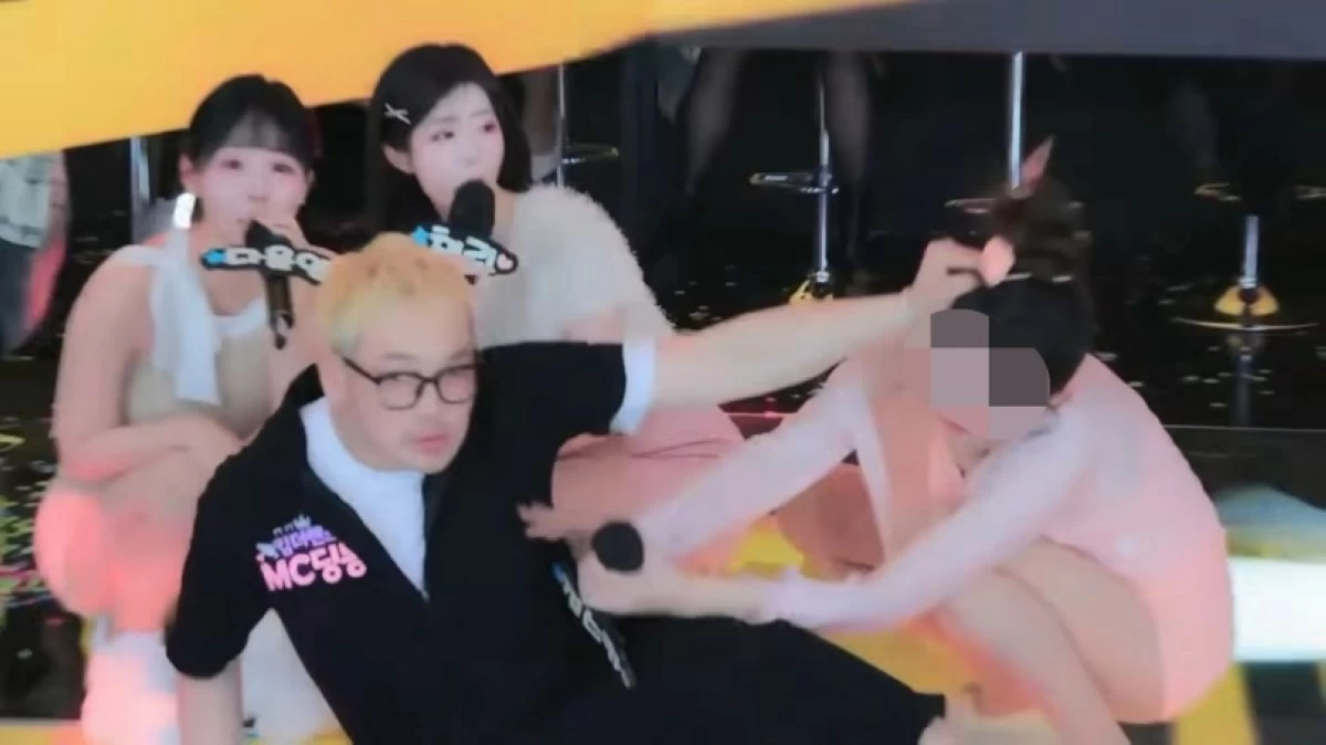 MC Dingdong (2nd from right) grabbing the woman by the hair (Screenshot from YouTube video) 