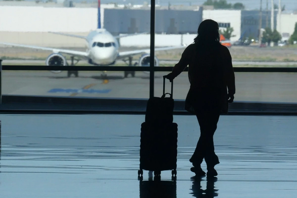FILE - A traveler looks out at an airplane at Salt Lake City International Airport, in Salt Lake City, July 3, 2024. (AP Photo/Rick Bowmer, File)