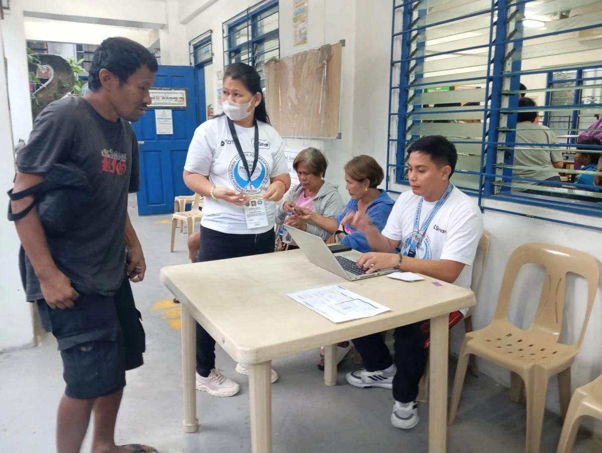 A PWD is assisted by PPCRV volunteers as he tries to look for his name in the voters' list (photo by Nel Andrade)

