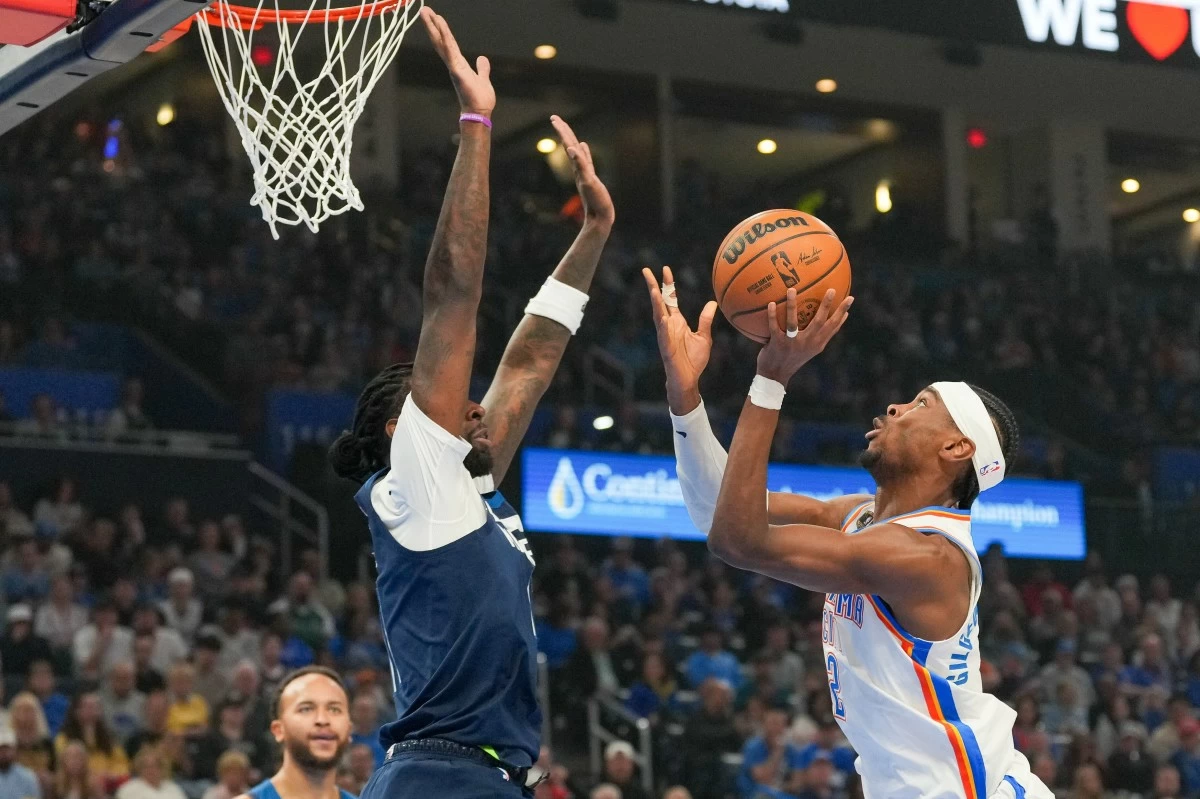 Oklahoma City Thunder guard Shai Gilgeous-Alexander, right, shoots over Minnesota Timberwolves center Naz Reid,  front left, during the first half of an NBA basketball game, Sunday, March 15, 2026, in Oklahoma City. (AP Photo/Kyle Phillips)