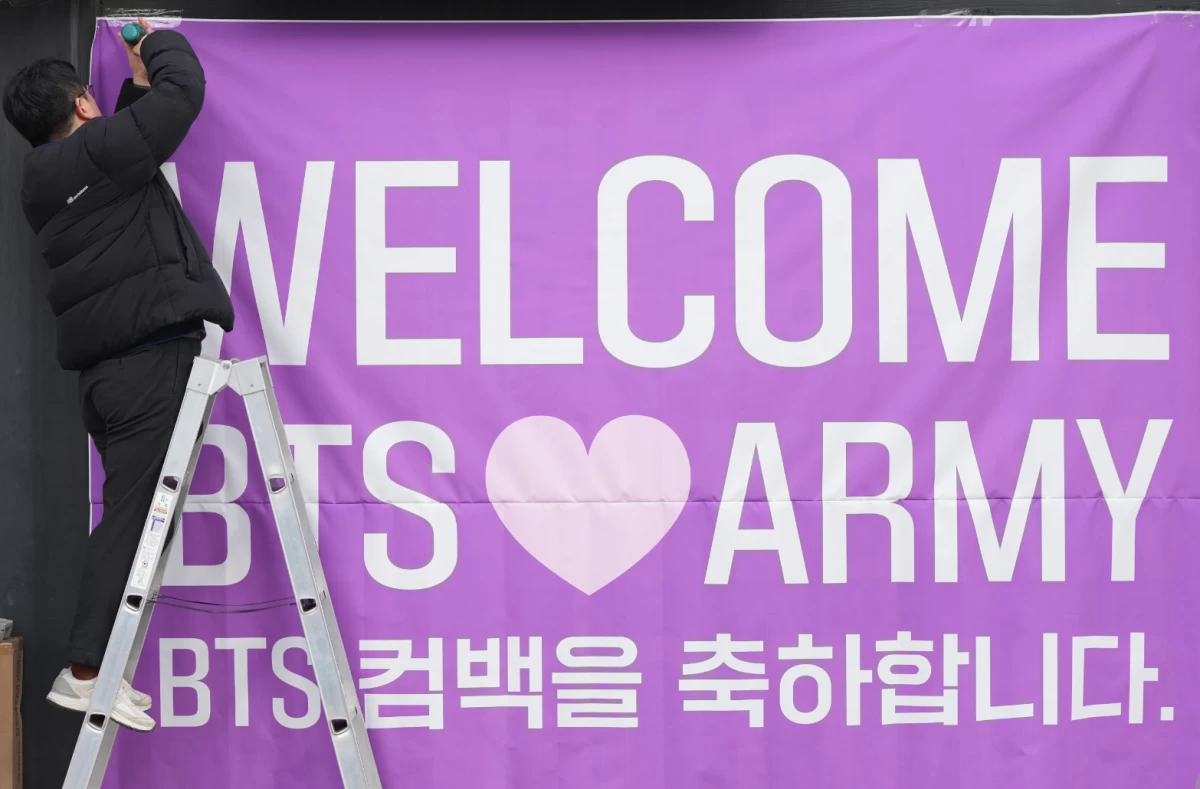 A man hangs a banner at a convenience store near the stage for a free concert by K-pop group BTS in Seoul, South Korea, on March 18. (AP)