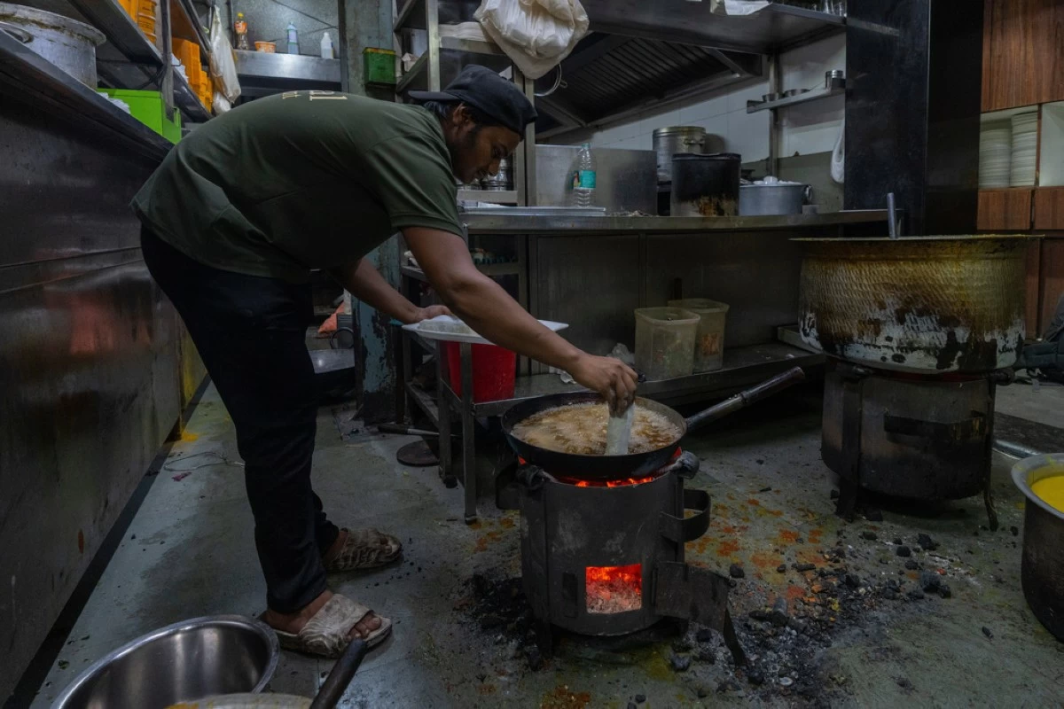 FILE - A cook at a restaurant prepares food over a charcoal stove following a shortage of liquefied petroleum gas in Mumbai, India, Wednesday, March 11, 2026. (AP Photo/Rafiq Maqbool)