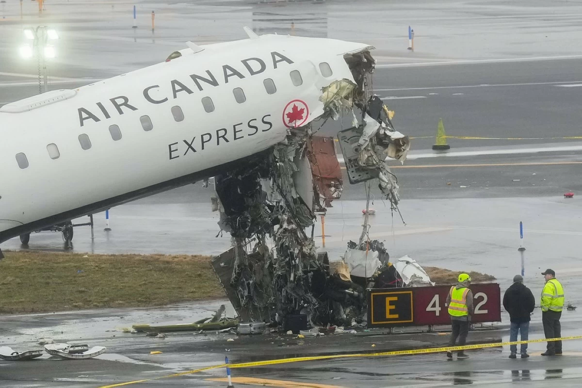 Officials investigate the site, Monday, March 23, 2026, where an Air Canada jet came to rest after colliding with a Port Authority firetruck at LaGuardia Airport, shortly after landing Sunday night in New York. (AP Photo/Seth Wenig)