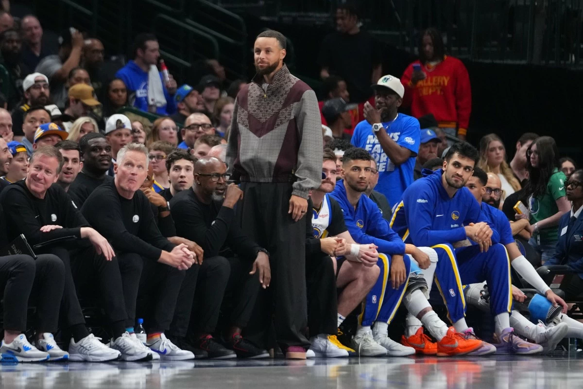 Golden State Warriors guard Stephen Curry looks on from the bench during the second half of an NBA basketball game against the Dallas Mavericks Monday, March 23, 2026, in Dallas. (AP Photo/Julio Cortez)