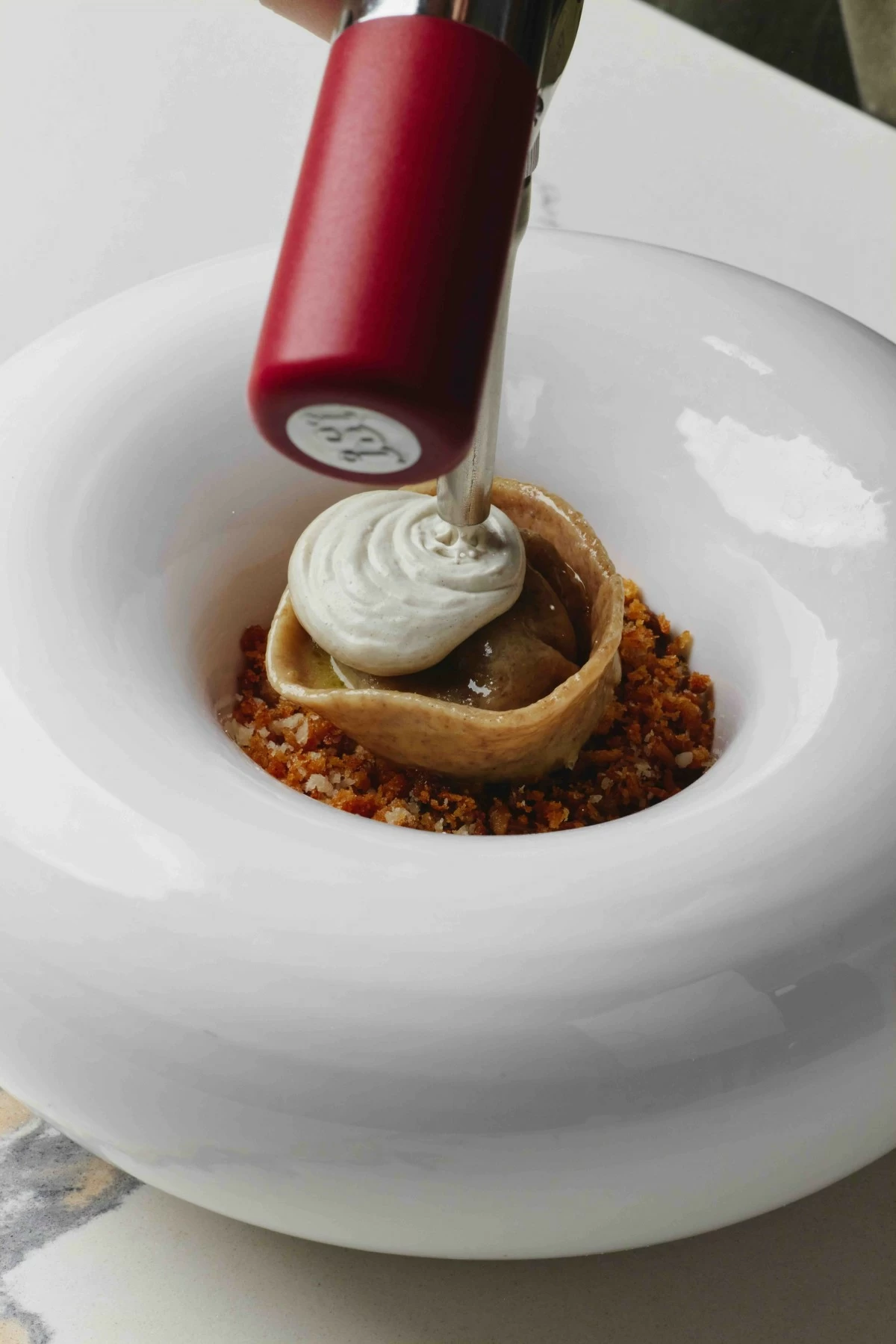 SLOTH BOWL Cappelletti filled with caramelized onions, set over braised beef and breadcrumbs, finished with a burnt onion espuma