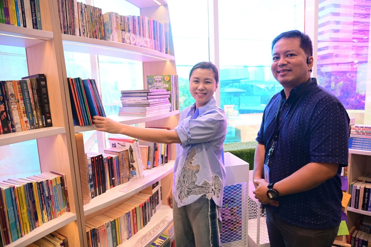 Book Nook Pioneer Shereen Sy officially places the donated research journals on the Book Nook shelves, alongside ADMU Research Communications Head Timothy James M. Dimacali, SM APF.
