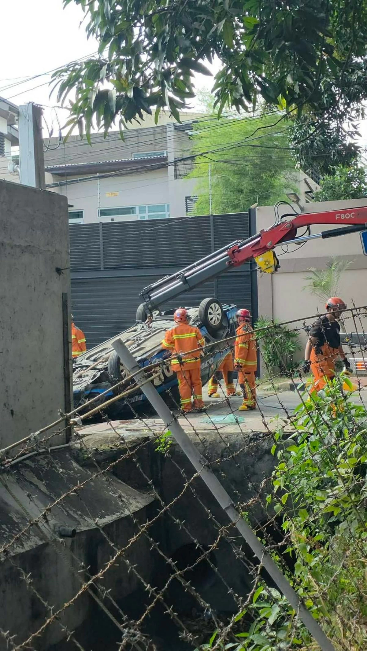 A police patrol vehicle lies overturned after falling into a creek in New Manila, Quezon City. The QCPD said the unit lost control before crashing into a barrier and plunging into the canal. (Photo from QCPD-PIO)