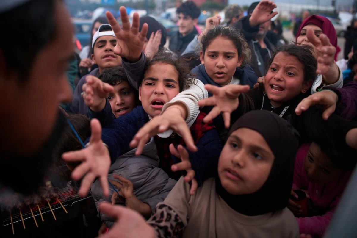 DISPLACED families extend their hands while waiting for donated food beside the tents they use as shelters after fleeing Israeli bombardment in southern Lebanon, in Beirut, Lebanon, Thursday, April 9, 2026. (AP)