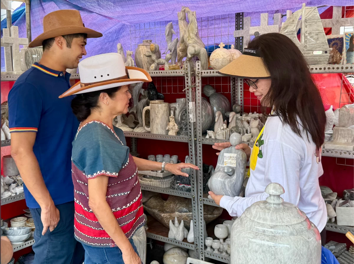 The First Lady and Vinny Marcos tour the exhibition booths during the 30th Rodeo Masbateño Festival. Mrs. Marcos took a close interest in the local crafts, asking vendors about their materials and earmarking several items to be featured in an upcoming exhibition for the ASEAN summit.