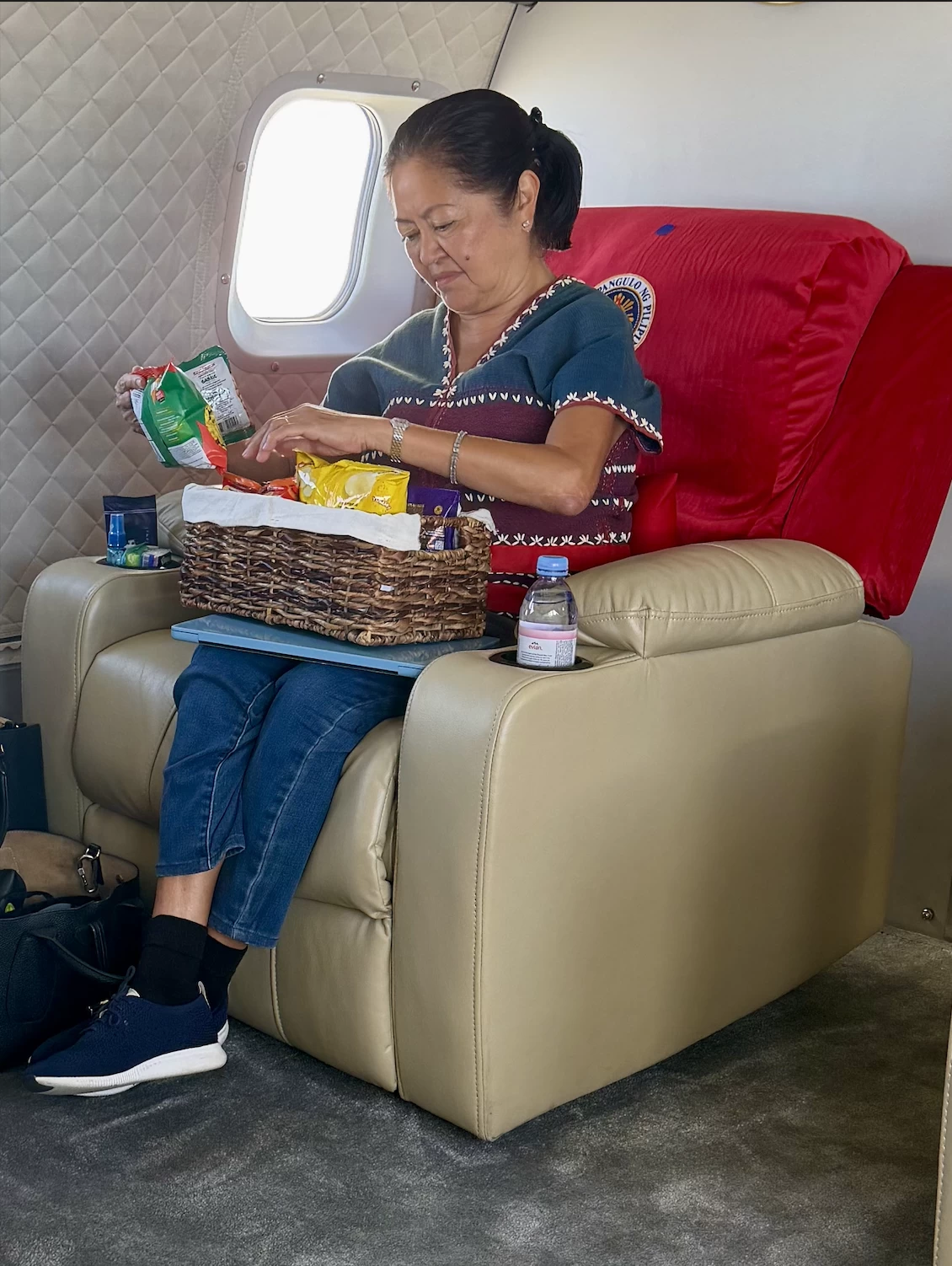 First Lady Liza Araneta-Marcos picks out a snack from a basket of treats inside the presidential cabin. During the flight to Masbate, the atmosphere remained informal as she passed around bags of chips and snacks for the media delegation to share.