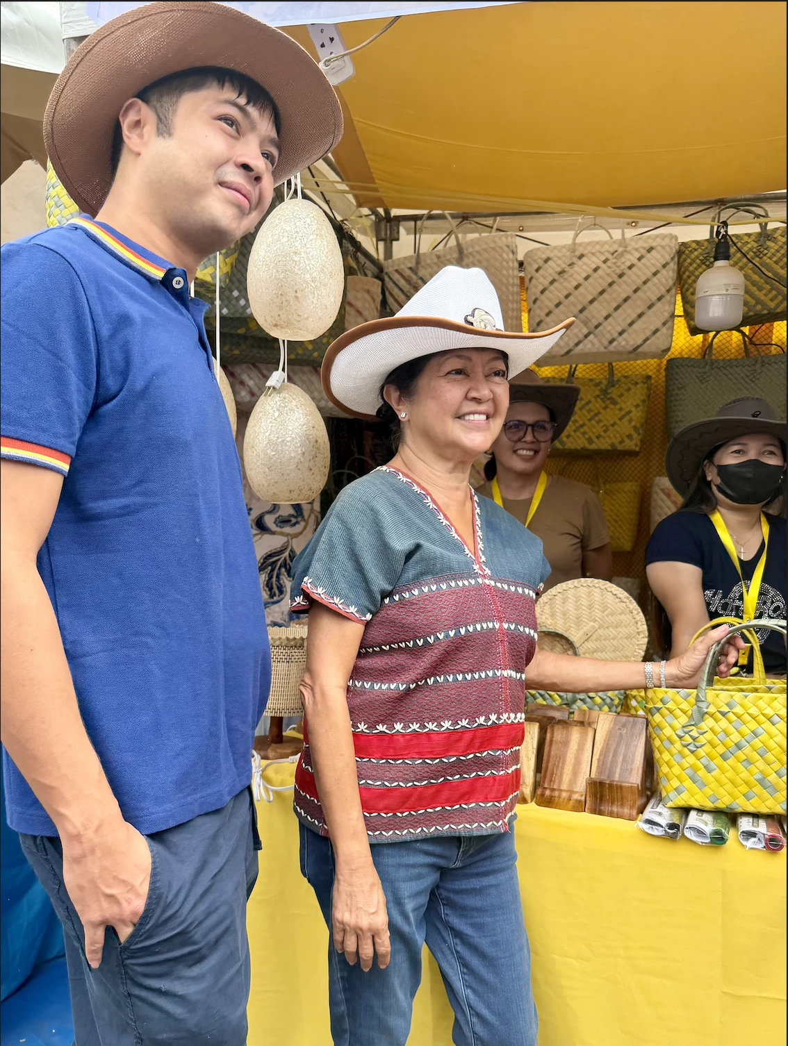 The First Lady and Vinny Marcos tour the exhibition booths during the 30th Rodeo Masbateño Festival. Mrs. Marcos took a close interest in the local crafts, asking vendors about their materials and earmarking several items to be featured in an upcoming exhibition for the ASEAN summit.