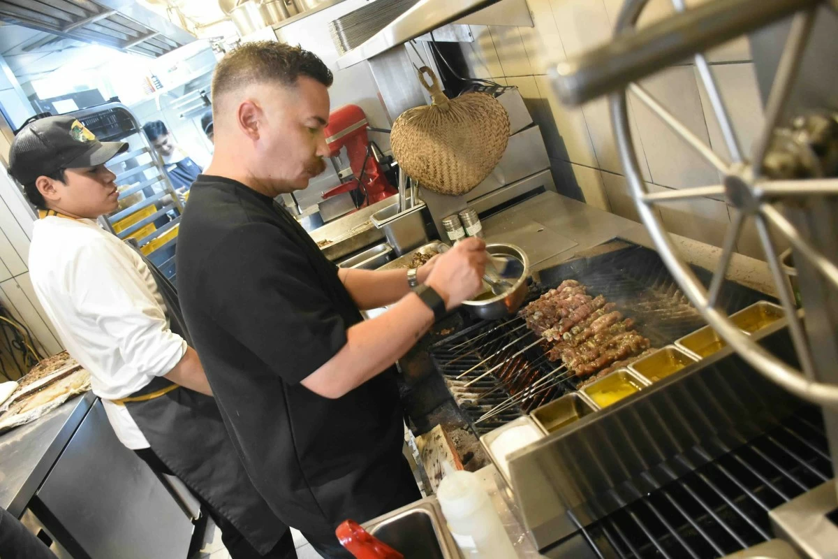 BY THE FIRE Josh Boutwood at the open-fire grill of Ember by Josh Boutwood, where smoke and heat shape the menu (Photo courtesy of SMB)