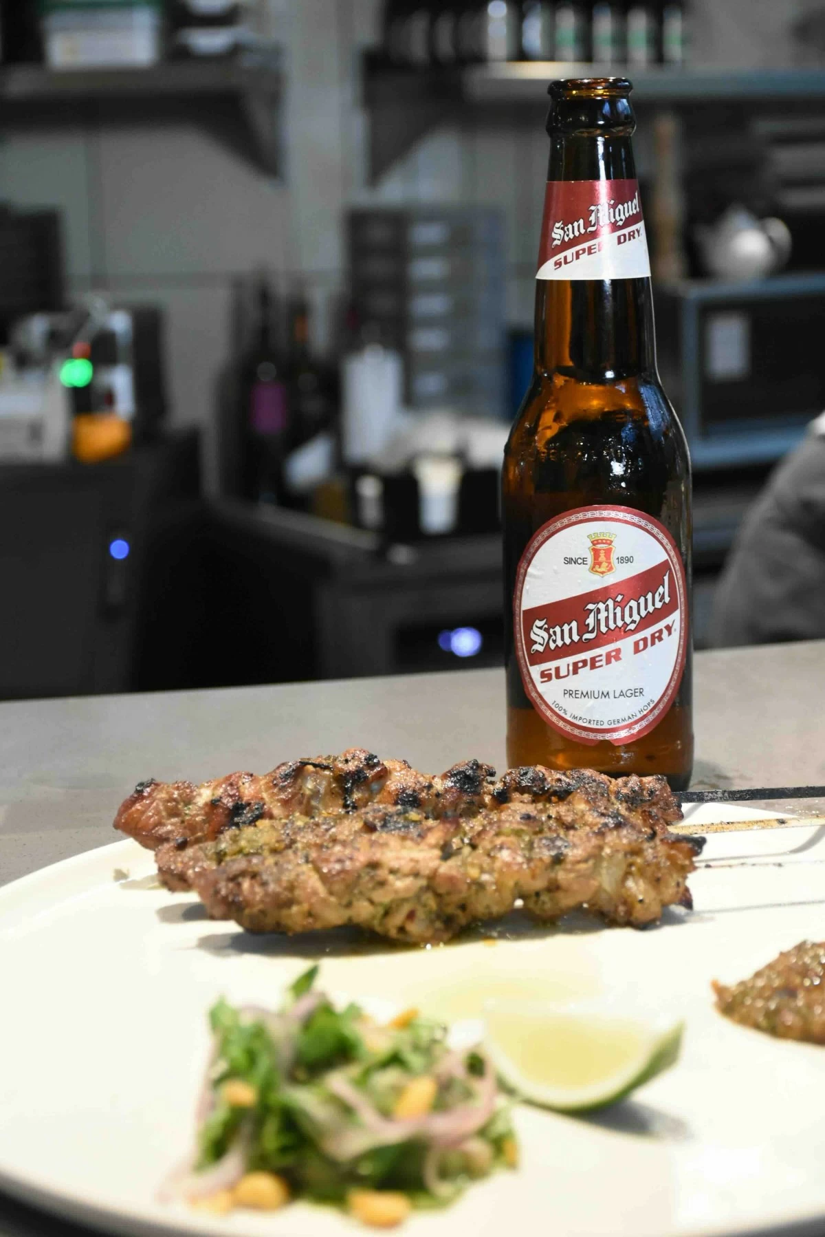 GRILLED SKEWERS Marinated pork skewers with jaew sauce, herb salad, and lime, paired with Super Dry to keep each bite clean and crisp. (Photo courtesy of SMB)