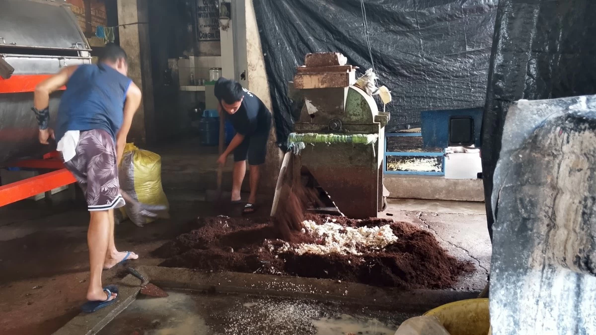 Kitchen waste is mixed with cocopeat and placed in a rotary composter to be converted into organic fertilizer.