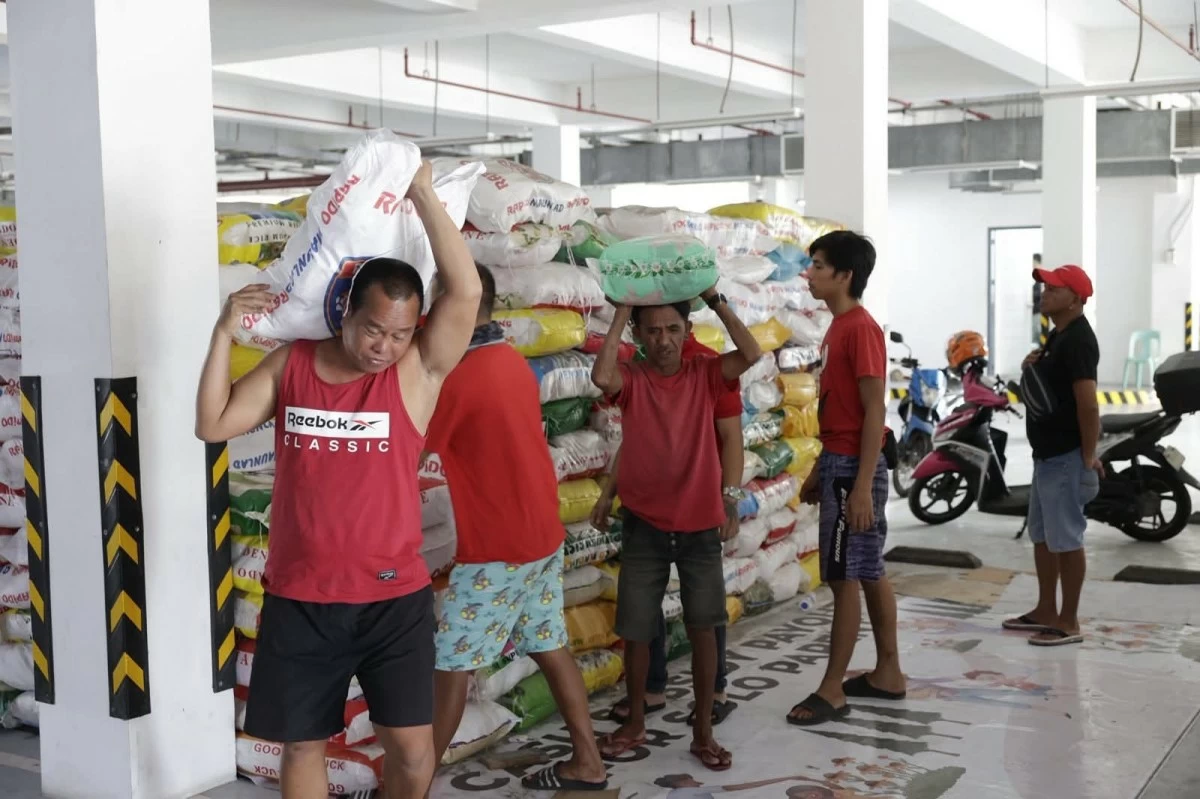 Residents in Obando, Bulacan carry sacks of rice provided by the Navotas City government as relief assistance for families affected by smoke from the Navotas Sanitary Landfill Facility (NSFL) fire. (Photo courtesy of Tiangco/Facebook)