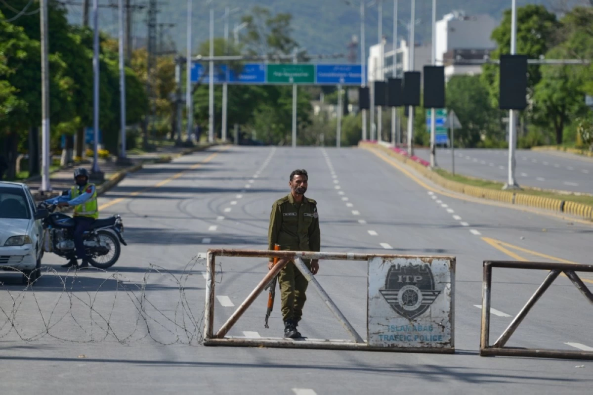 A police officer stands guard at a checkpoint on a barricaded road to ensure security ahead of the second round of the U.S. Iran officials talks, in Islamabad, Pakistan, Sunday, April 19, 2026. (AP Photo/M.A. Sheikh)