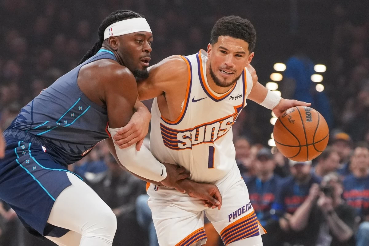 Phoenix Suns guard Devin Booker, right, drives past Oklahoma City Thunder guard Luguentz Dort during the first half in Game 2 of a first-round NBA playoffs basketball series Wednesday, April 22, 2026, in Oklahoma City. (AP Photo/Kyle Phillips)