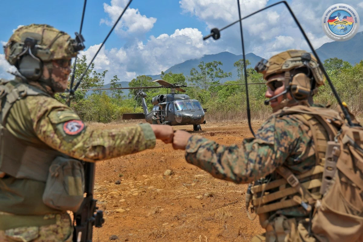 A Special Forces member from the Armed Forces of the Philippines (AFP) and a U.S. Marine share a fist bump in front of a Black Hawk helicopter during the Counter-Landing Live Fire Exercise - West in Apurawan Beach, Aborlan, Palawan on April 27, 2026 as part of Exercise Balikatan. (Photo by SSg Ambay PA/PAOAFP)