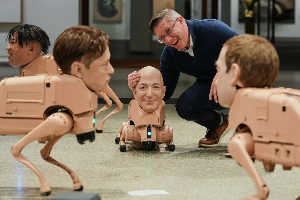 Artist Beeple, Mike Winkelmann, poses inside his installation titled Regular Animals, with robots in the likeness of Kim Jong Un, left, Elon Musk, second left, Jeff Bezos, center, and Mark Zuckerberg, right, at the Neue Nationalgalerie museum in Berlin, Germany, Tuesday, April 28, 2026. (AP Photo/Markus Schreiber)