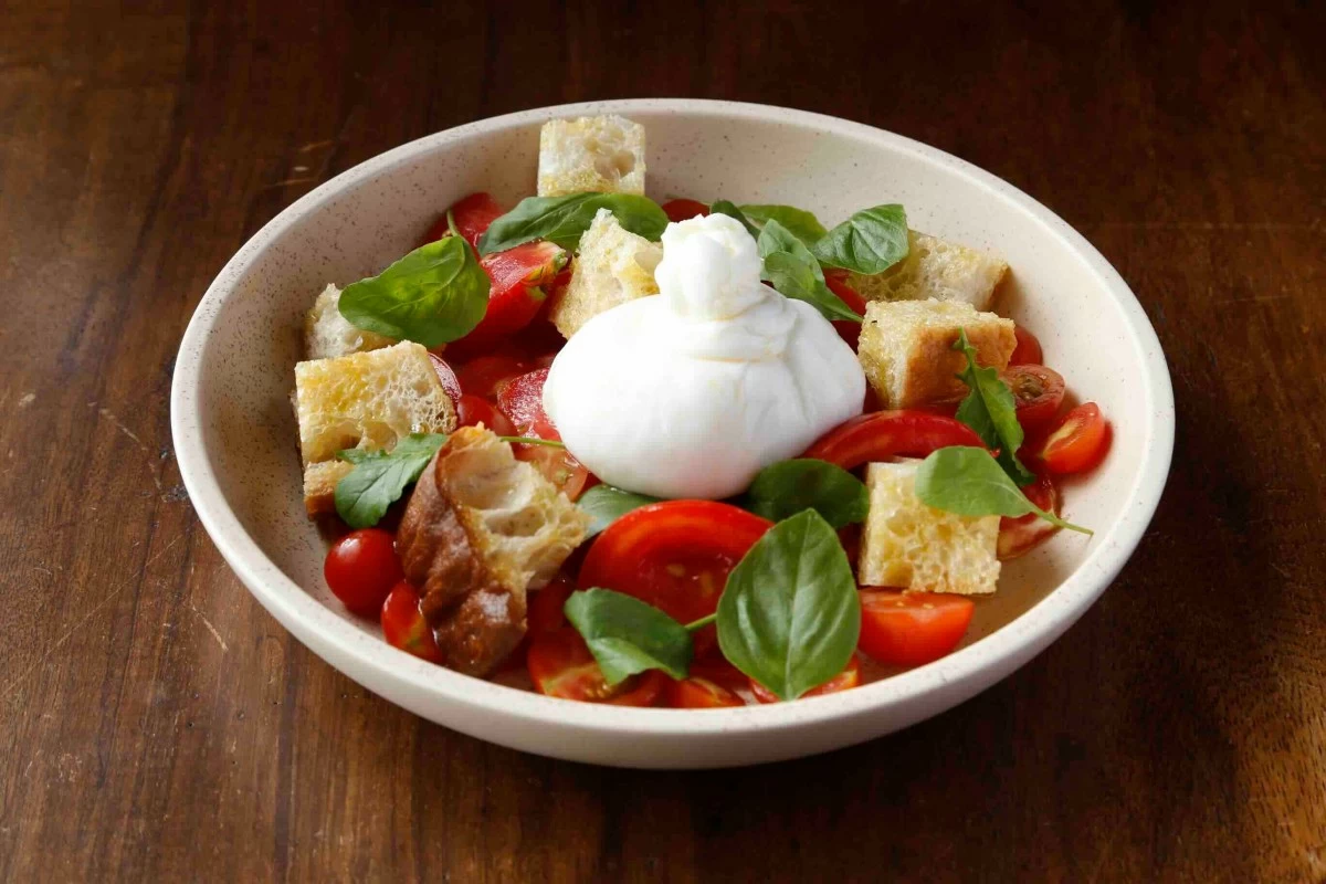 FRESH SALAD Burratina panzanella with tomatoes, greens, house croutons, and honey vinaigrette, served as a light starter. (Photo: Flour Pot Bistro and Bakery)