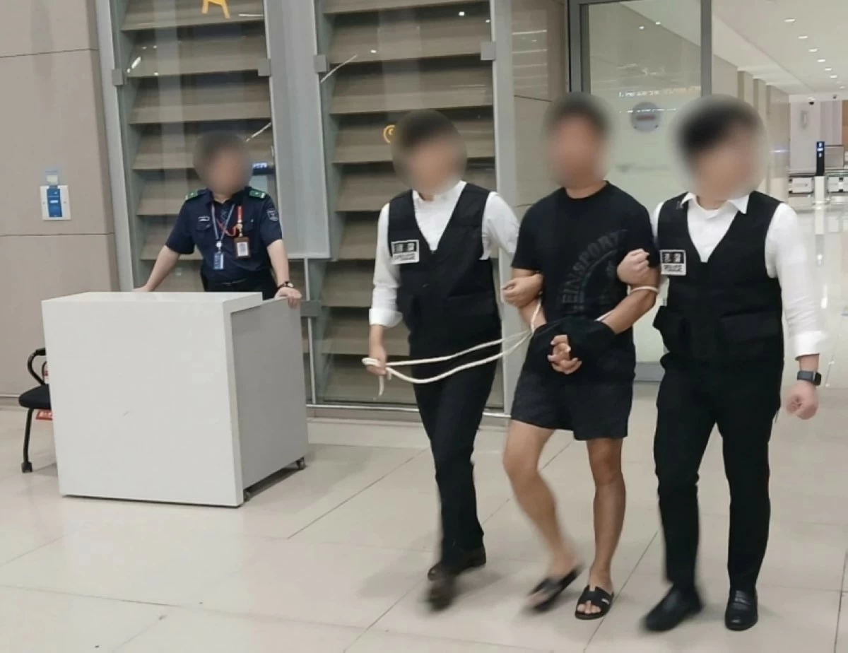 The leader of a hacking organization (center) is escorted by the police as he arrives at Incheon International Airport on Aug. 22, 2025 (Korea's Ministry of Justice)