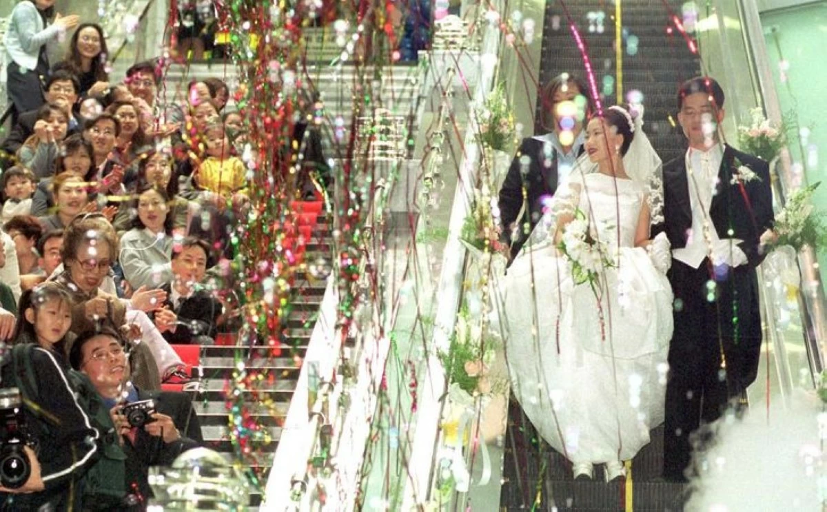 A newlywed couple rides an escalator during their wedding ceremony at Noksapyeong Station in Seoul in this 2001 file photo. (Photo: The Korea Times)
