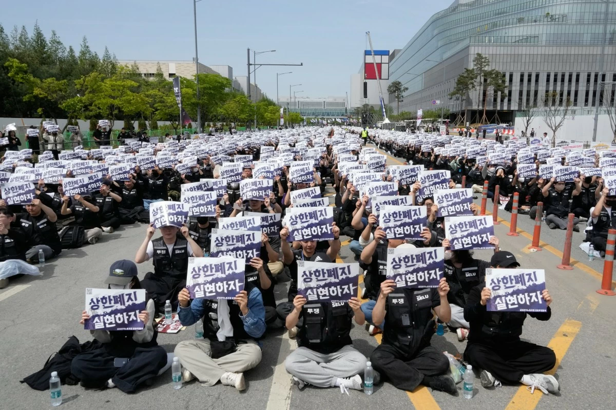 FILE - Members of the Samsung Electronics labor union hold up their cards during a rally demanding higher bonuses at its computer chip complex in Pyeongtaek, South Korea, on April 23, 2026. The letters read 