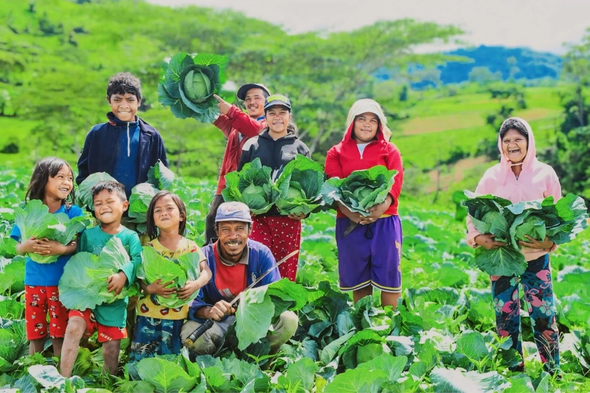 A FAMILY OF FARMERS—the hands behind Café sa Bukid’s fresh, locally grown produce—smile for a photo while holding freshly harvested cabbages.