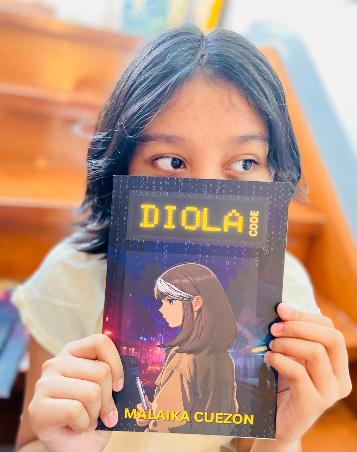 FIRST TIME AUTHOR - 13-year-old Malaika Cuezon holds up her first novel, Diola Code.