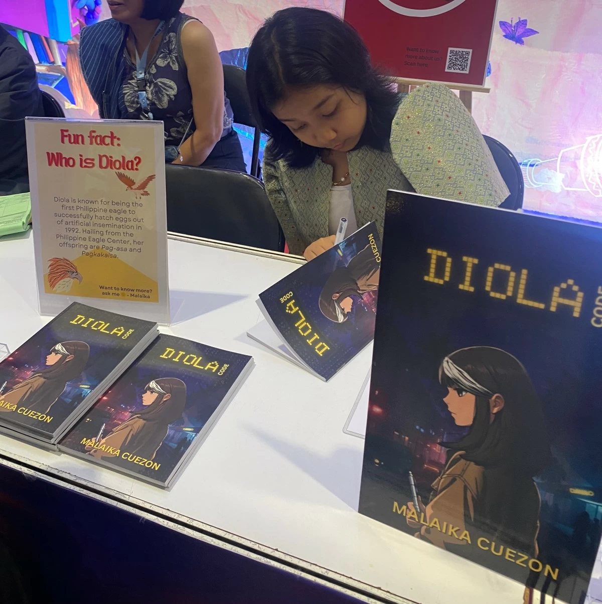 MALAIKA CUEZON signing copies of Diola Code at the Philippine Book Festival 2026.