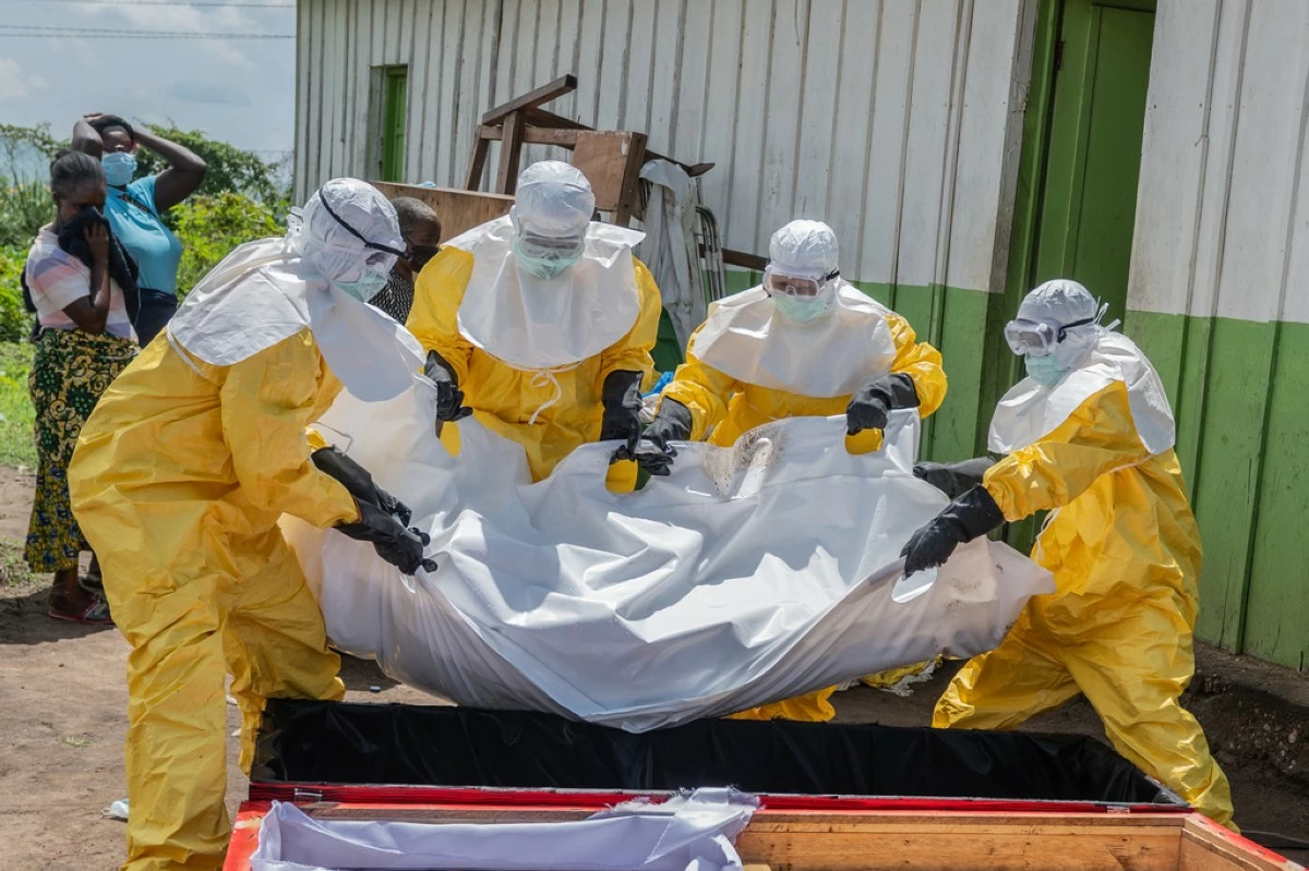Red Cross workers carry the body of a person who died of Ebola into a coffin at a health center in Rwampara, Congo, Wednesday, May 20, 2026. (AP Photo/Moses Sawasawa)