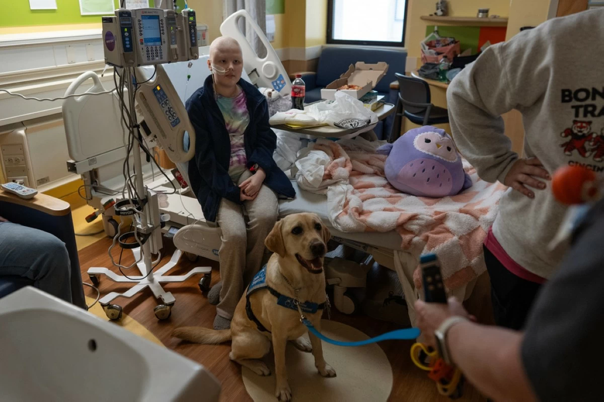 Cincinnati Children's Hospital facility dog Hadley sits at the feet of 11-year-old Bethany Striggles, who recently finished a chemotherapy treatment for bone cancer, in her room at Cincinnati Children's Hospital in Cincinnati, Monday, May 4, 2026. (AP Photo/Carolyn Kaster)