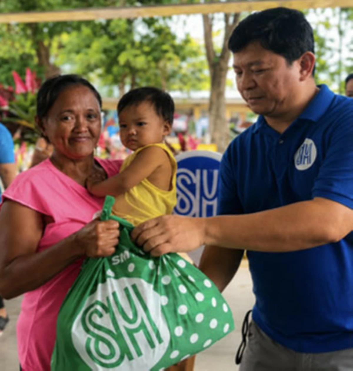 SM CITY Calamba Assistant Mall Manager and volunteer Earth Olazo extends assistance to a family during relief efforts for residents affected by tropical cyclones in July 2025. (SM City Calamba)