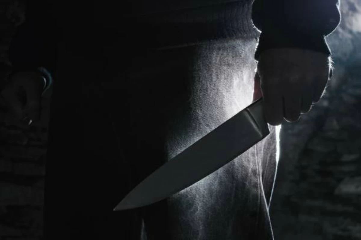 Dark photo of a man holding a big knife, crime concept.