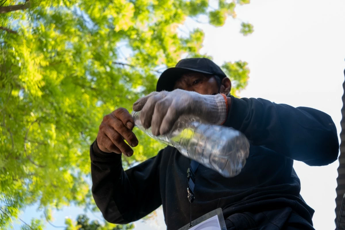Elmer removes the cap and label from a PET bottle as part of proper waste segregation, applying his training on which materials can be recovered and have value.