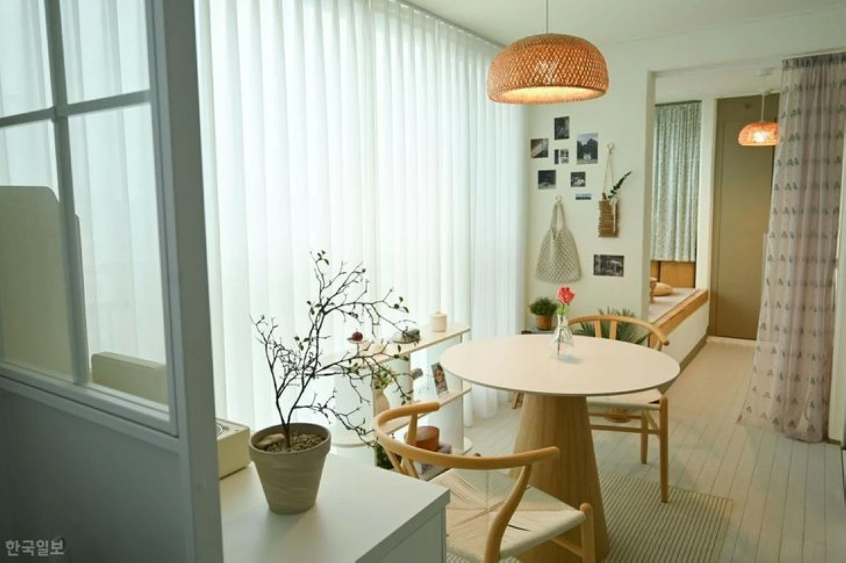 Kim Ri-ha transforms her living room balcony in Gimpo, Gyeonggi Province, into a sunlit home cafe furnished with a table, chairs and vintage props. She separates the long, continuous balcony space using a partition wall and curtains. (Photo: The Korea Times/Kang Ye-jin)