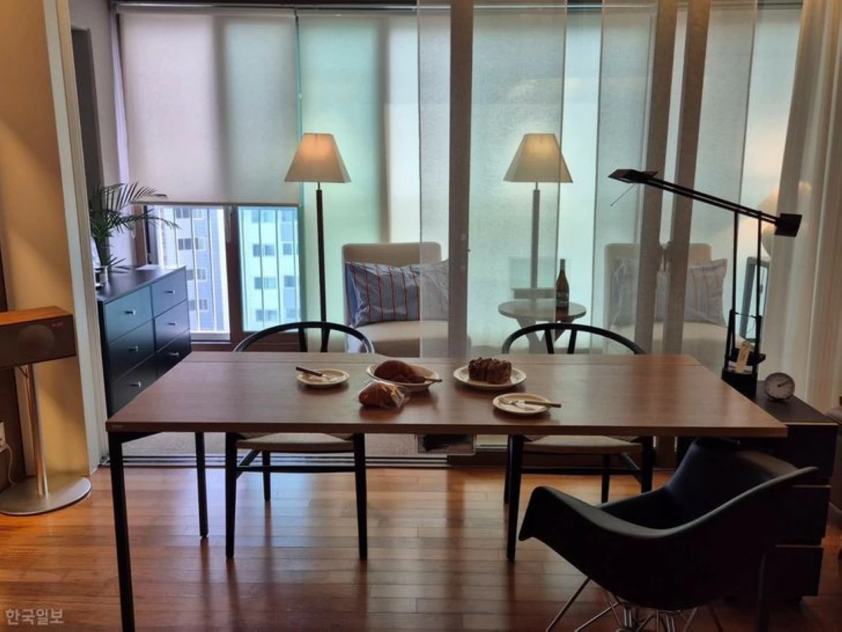 Yoon Ji-in's living room balcony is seen from inside her apartment. Blinds cover the windows to block the view of the neighboring building, while the single sofa and table face inward toward the living room. (Photo: The Korea Times/Kim Na-yeon)