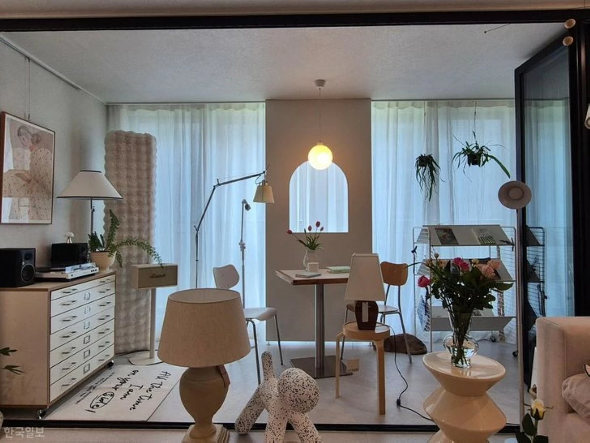 The expanded living room balcony in Oh Jung-won's apartment serves as a separate space by keeping the existing folding doors. She furnished the area with a table, storage unit and magazine rack to create a home cafe and photo zone. (Photo: The Korea Times/Kim Na-yeon)