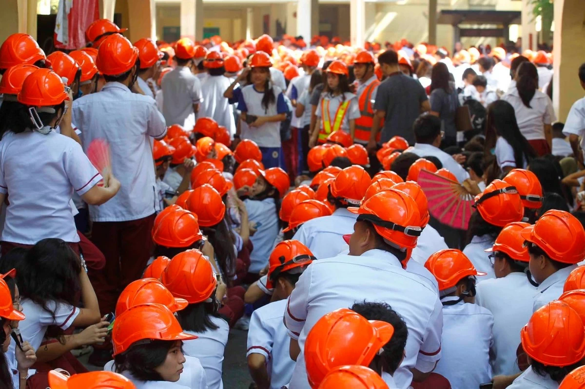 Students of Araullo High School practice the “duck, cover, and hold” protocol during the National Simultaneous Earthquake Drill.