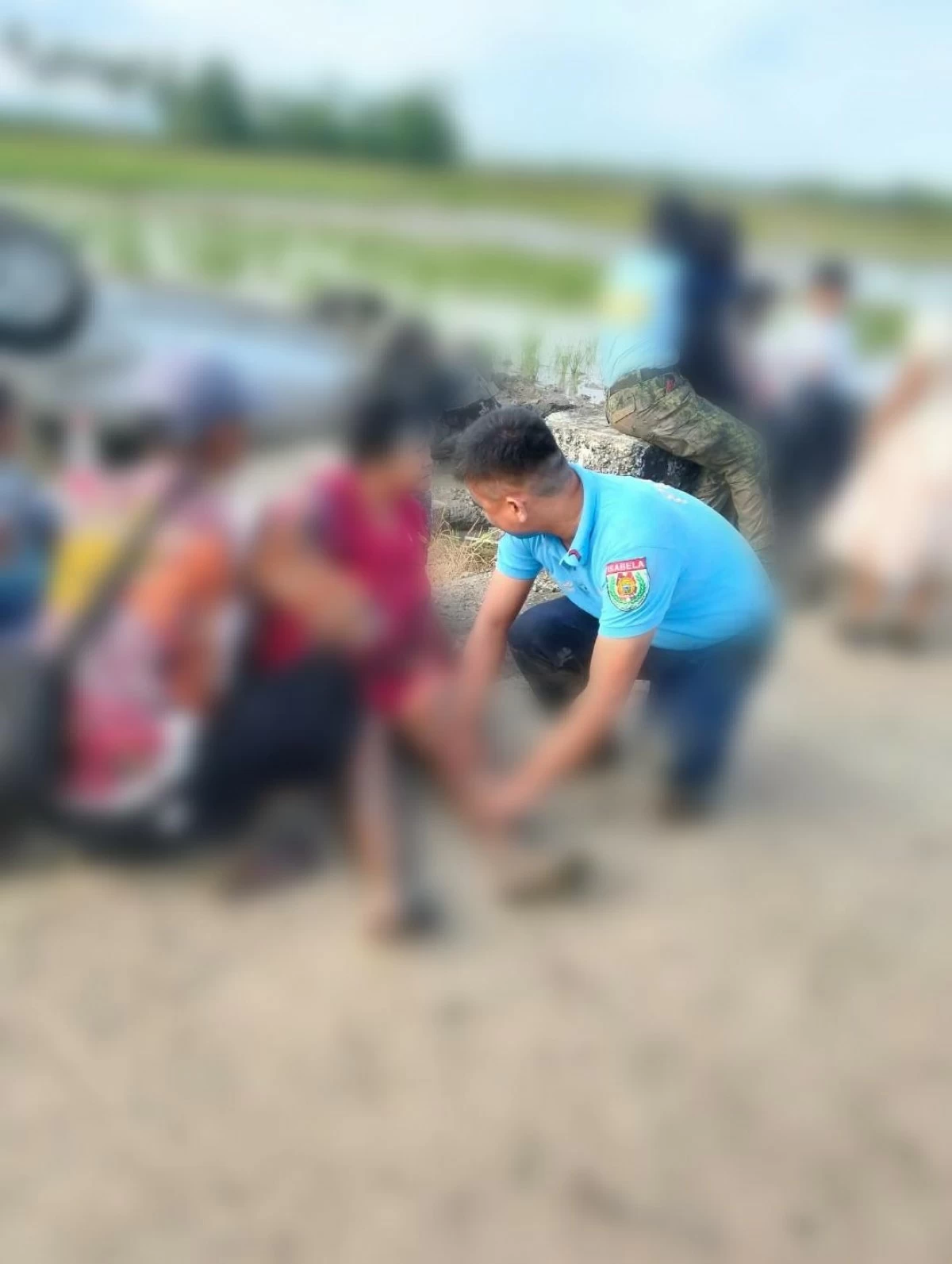 TWO police officers assist two persons injured in an accident in Alicia, Isabela on Thursday. (Photo via Liezle Inigo) 