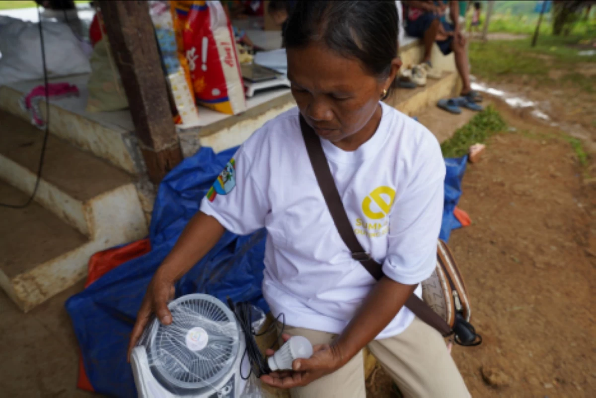 Jovita, a 53-year-old resident in Barangay New Aklan in Glan, Sarangani province, unboxes the solar lamp with built-in fan at their evacuation site on June 16, 2026. 
