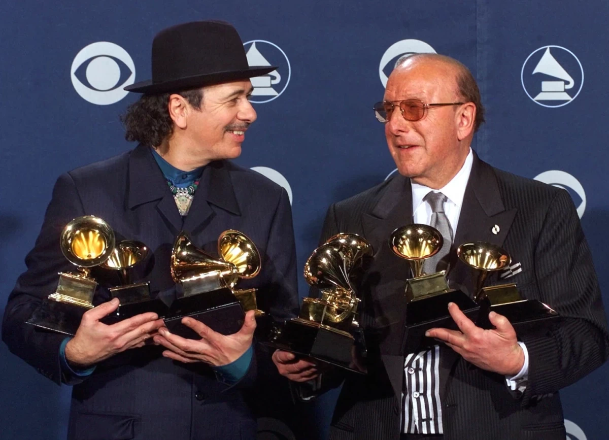 Carlos Santana, left, and producer Clive Davis pose with their Grammys at the 42nd Grammy Awards in Los Angeles, on Feb. 23, 2000. (AP Photo/Reed Saxon, File)