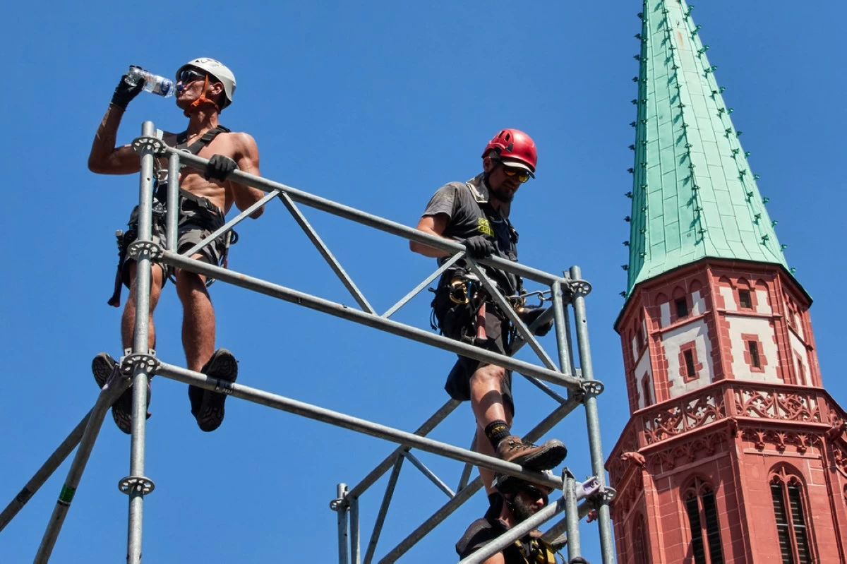 A worker drinks water as he sets up a stage for the upcoming Ironman triathlon, Frankfurt, Germany, Thursday, June 25, 2026. (AP Photo/Michael Probst)