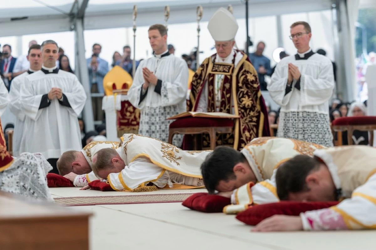 Four bishops lie on the floor as they are given episcopal consecration during a Mass in a tent set up outside the Society of St. Pius X seminary, in Econe, Switzerland, Wednesday, July 1, 2026. (Cyril Zingaro/Keystone via AP)