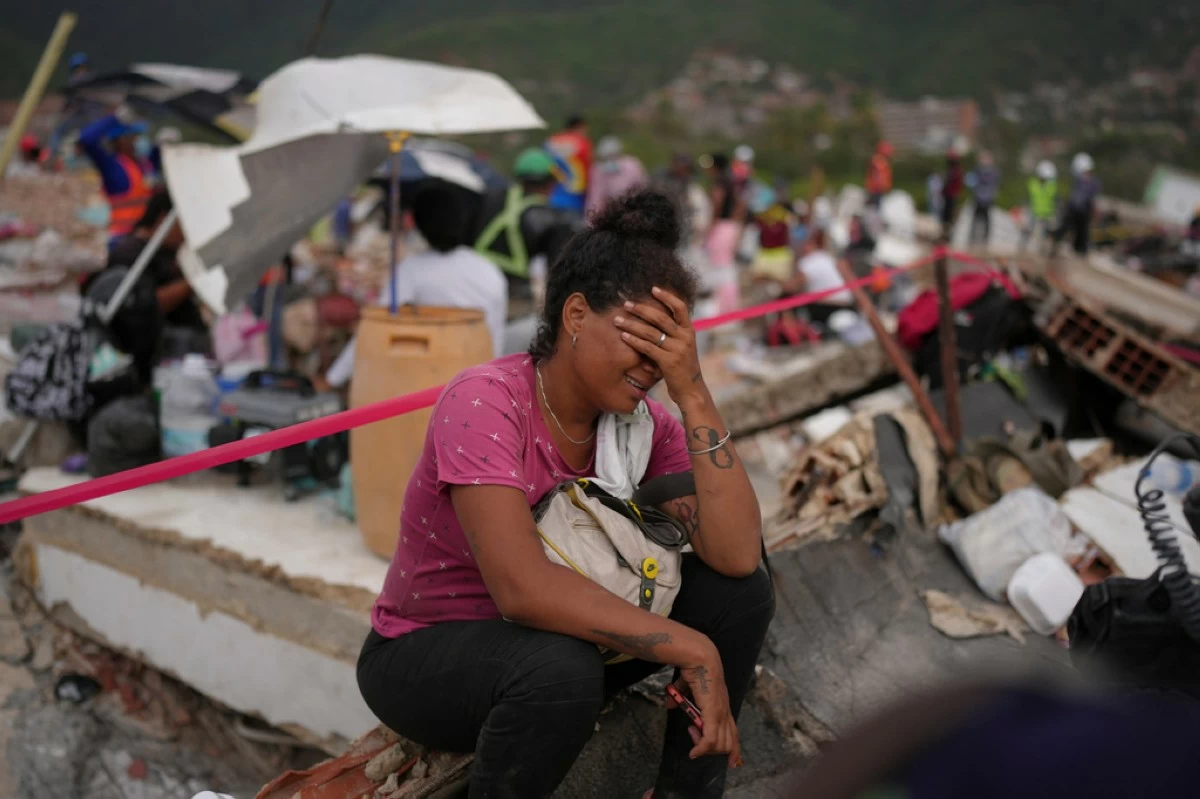 Khaterine Roa cries as members of the Los Angeles County Fire Department search for survivors at a building that collapsed during the earthquakes that struck La Guaira, Venezuela, Tuesday, June 30, 2026. (AP Photo/Matias Delacroix)