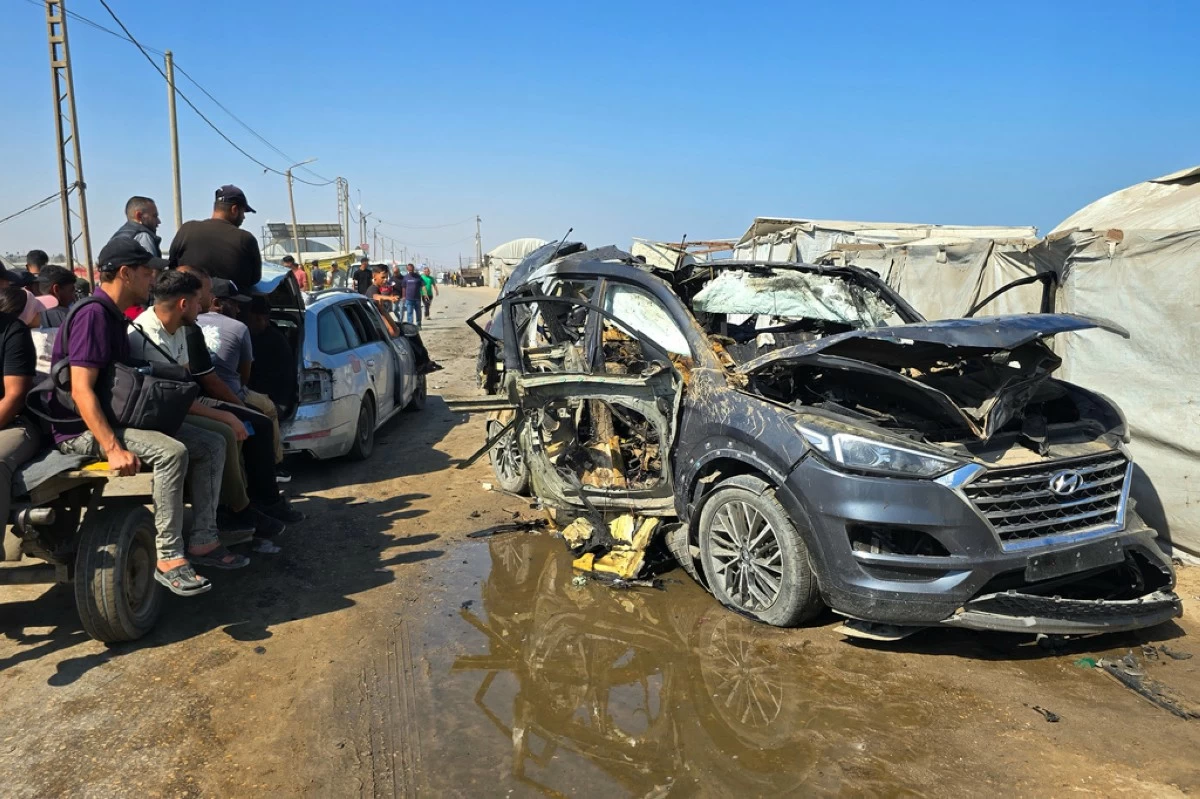 Palestinians look at a destroyed car following an Israeli military strike in Khan Younis, southern Gaza Strip, Monday, July 6, 2026, that, according to hospital officials, killed at least one person. (AP Photo/Mohammad Jahjouh)