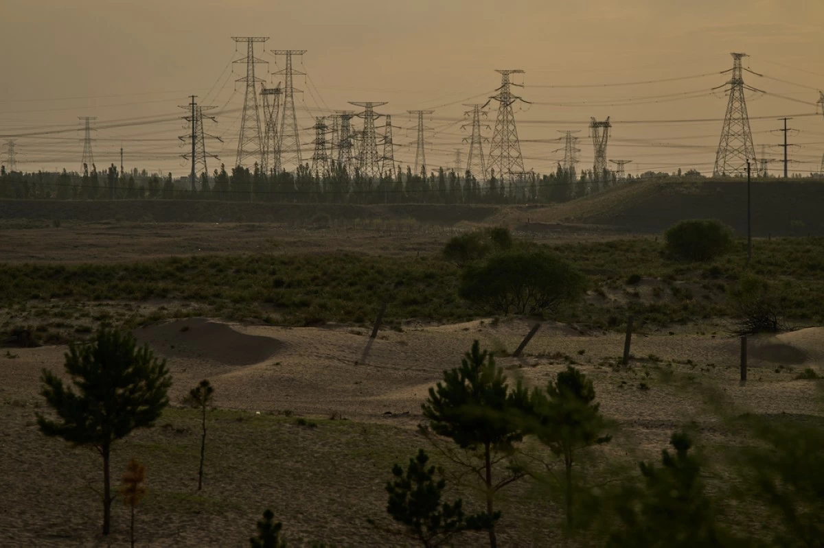 Electric pylons are seen in the horizon along sand dunes near Ordos in northern China's Inner Mongolia province on Thursday, June 11, 2026. (AP Photo/Ng Han Guan)