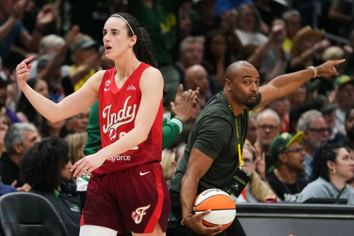 Indiana Fever guard Caitlin Clark points for possession as former Seattle Seahawks wide receiver Doug Baldwin, right, picks up the ball and calls for Seattle Storm possession during the first half of a WNBA basketball game, Tuesday, July 28, 2026, in Seattle. (AP Photo/Lindsey Wasson)