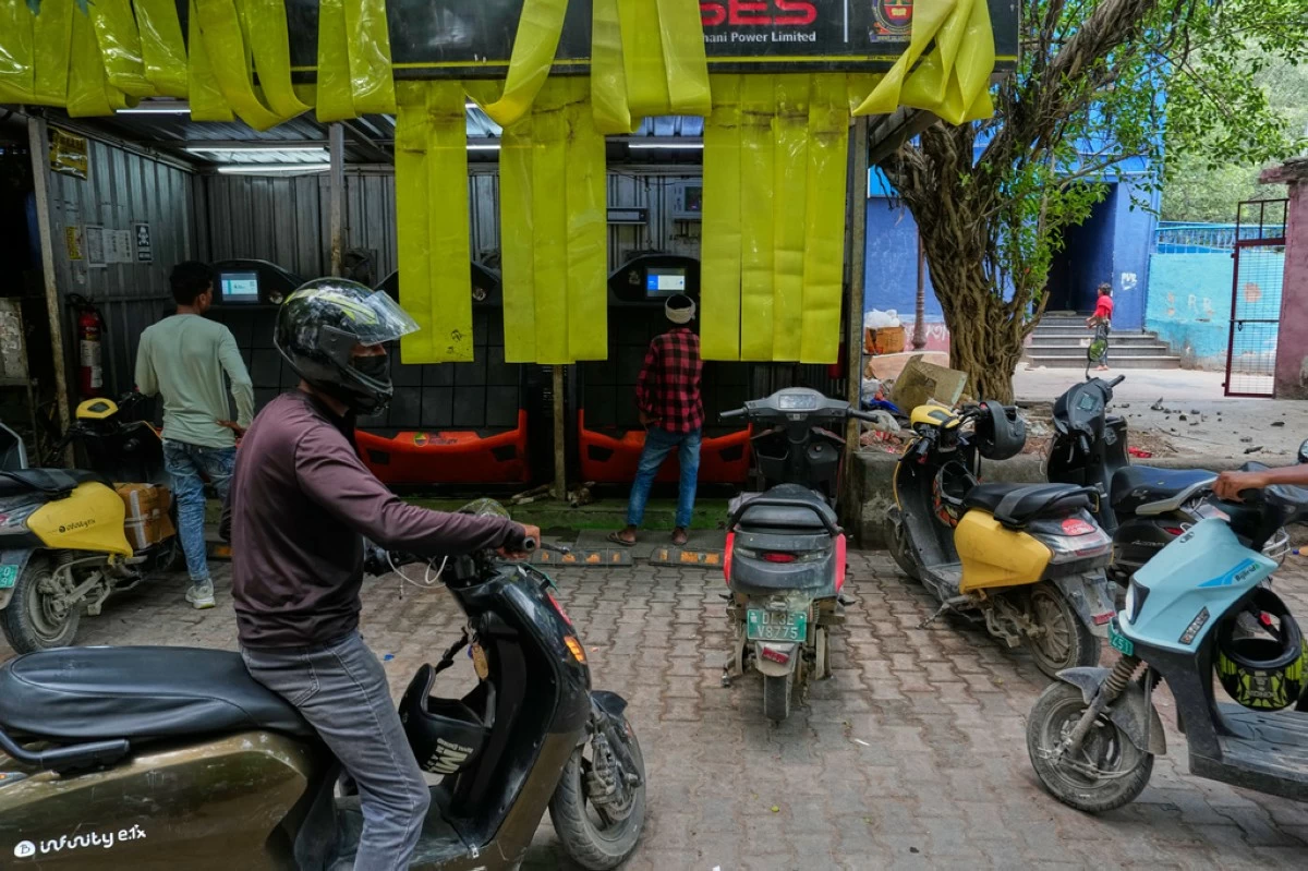 Delivery workers and drivers arrive at a battery-swapping station for electric vehicles in New Delhi, India, Monday, July 13, 2026. (AP Photo/Manish Swarup)